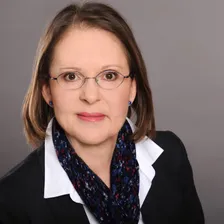 Martina Meyer im dunklen Jackett mit blau gemustertem Schal, freundlicher Blick in die Kamera
